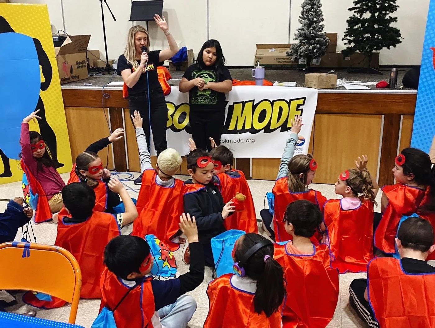 A classroom of second graders in red superhero capes on BookMode day